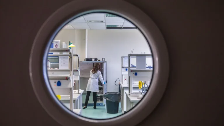 View through a round clean room window vision panel into a working laboratory