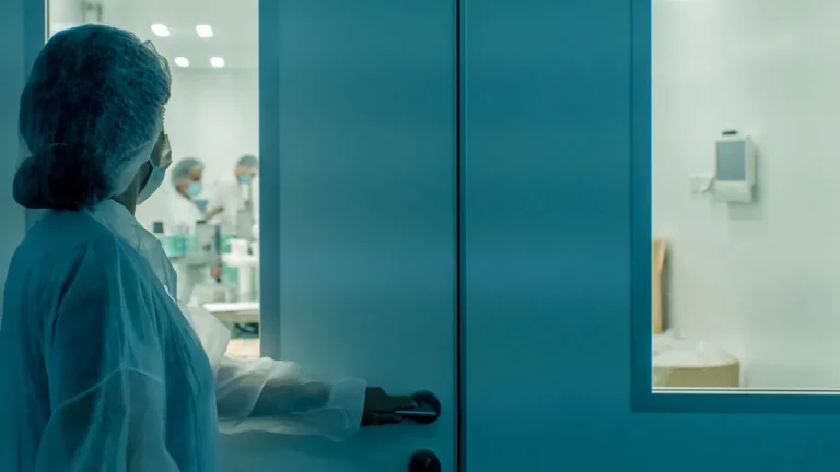 Clean room door operator in blue gown opening an airtight door