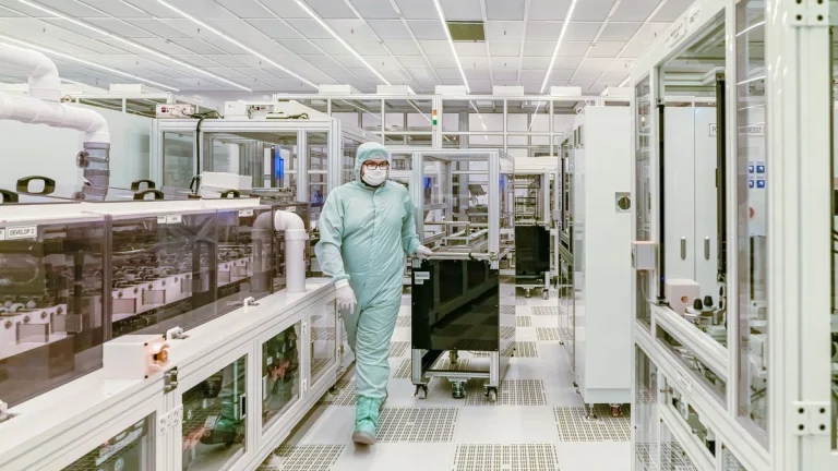 Scientist in protective gear walking through a high-tech cleanroom laboratory corridor