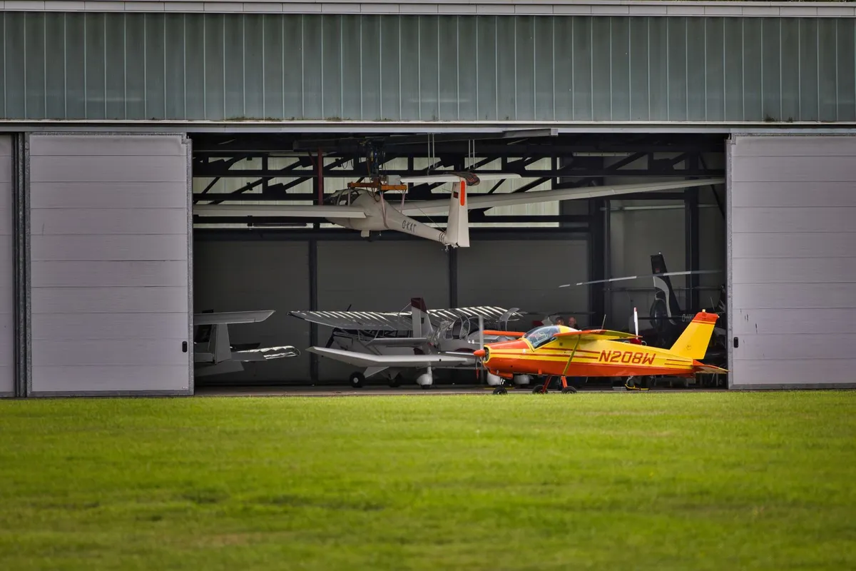 One leaf of a sliding hangar door parked open beside the clear opening of a small hangar