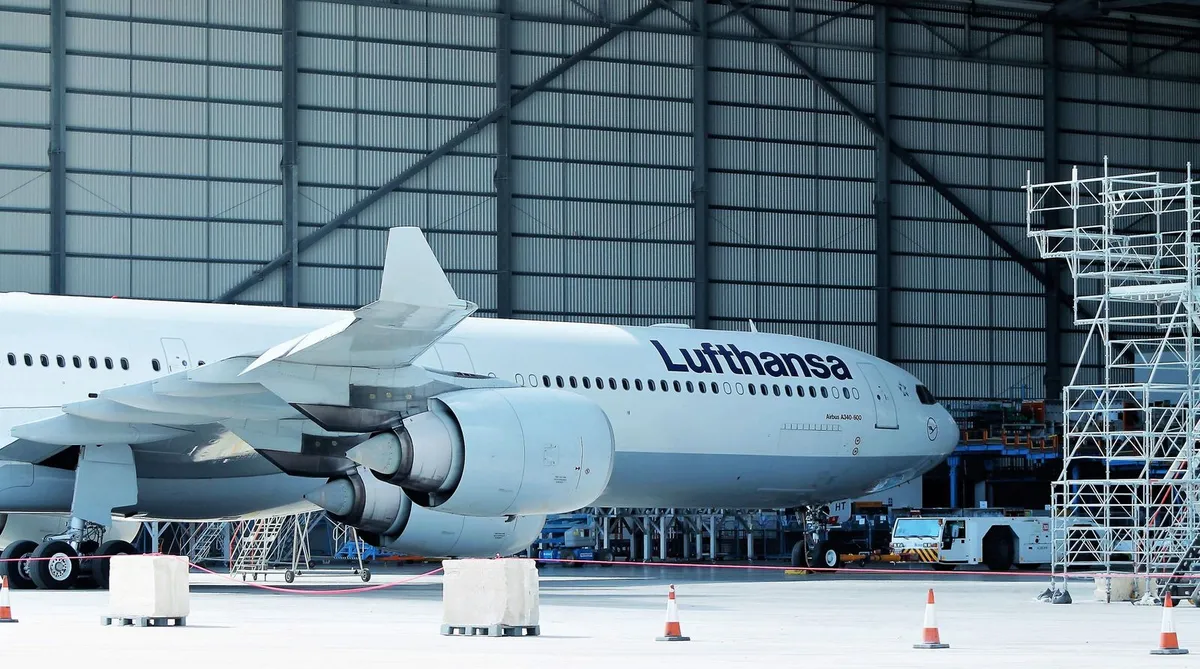 Airliner under maintenance inside a hangar with the tall sectional door wall closed behind