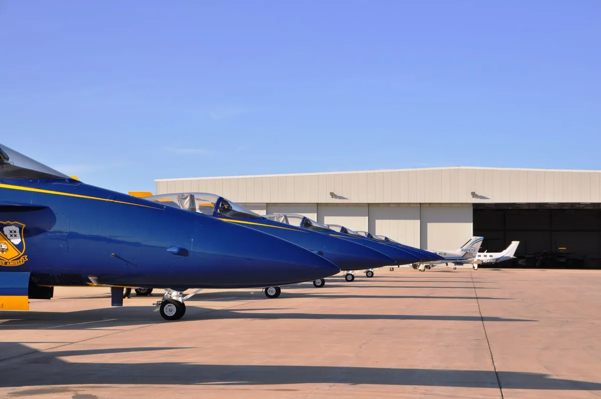 Jets parked on an apron in front of hangar door bays standing open