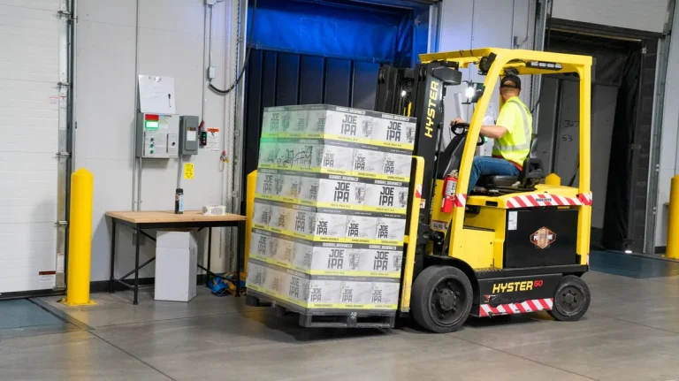 Forklift loading pallets at a refrigerated distribution dock with an insulated sectional door
