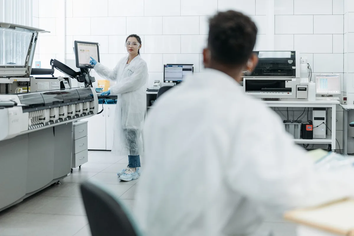 White pharmaceutical laboratory interior seen across glazed observation surfaces