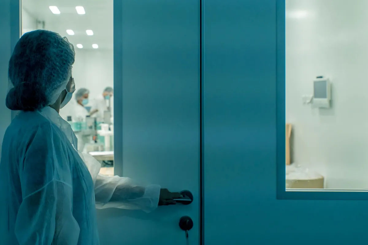 Un científico con equipo de protección entra a un entorno de laboratorio estéril, garantizando la limpieza. (fuente: Pexels, licencia comercial gratuita)