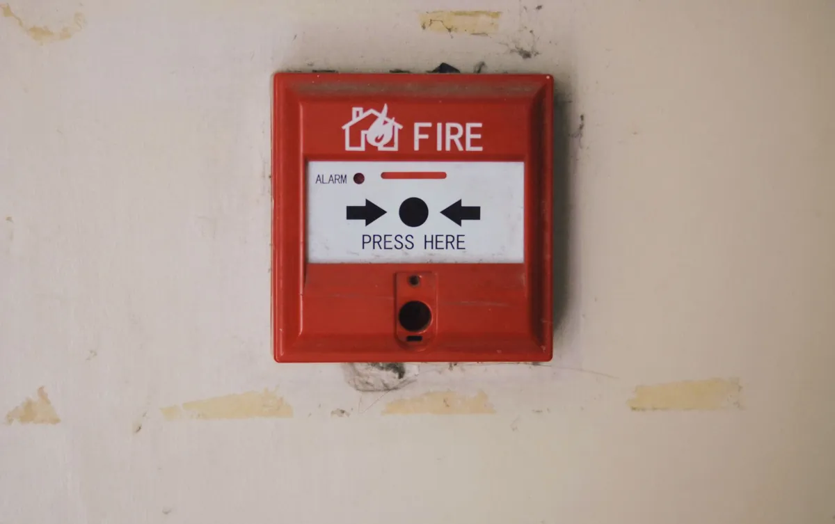 Red manual fire alarm call point mounted on a building wall