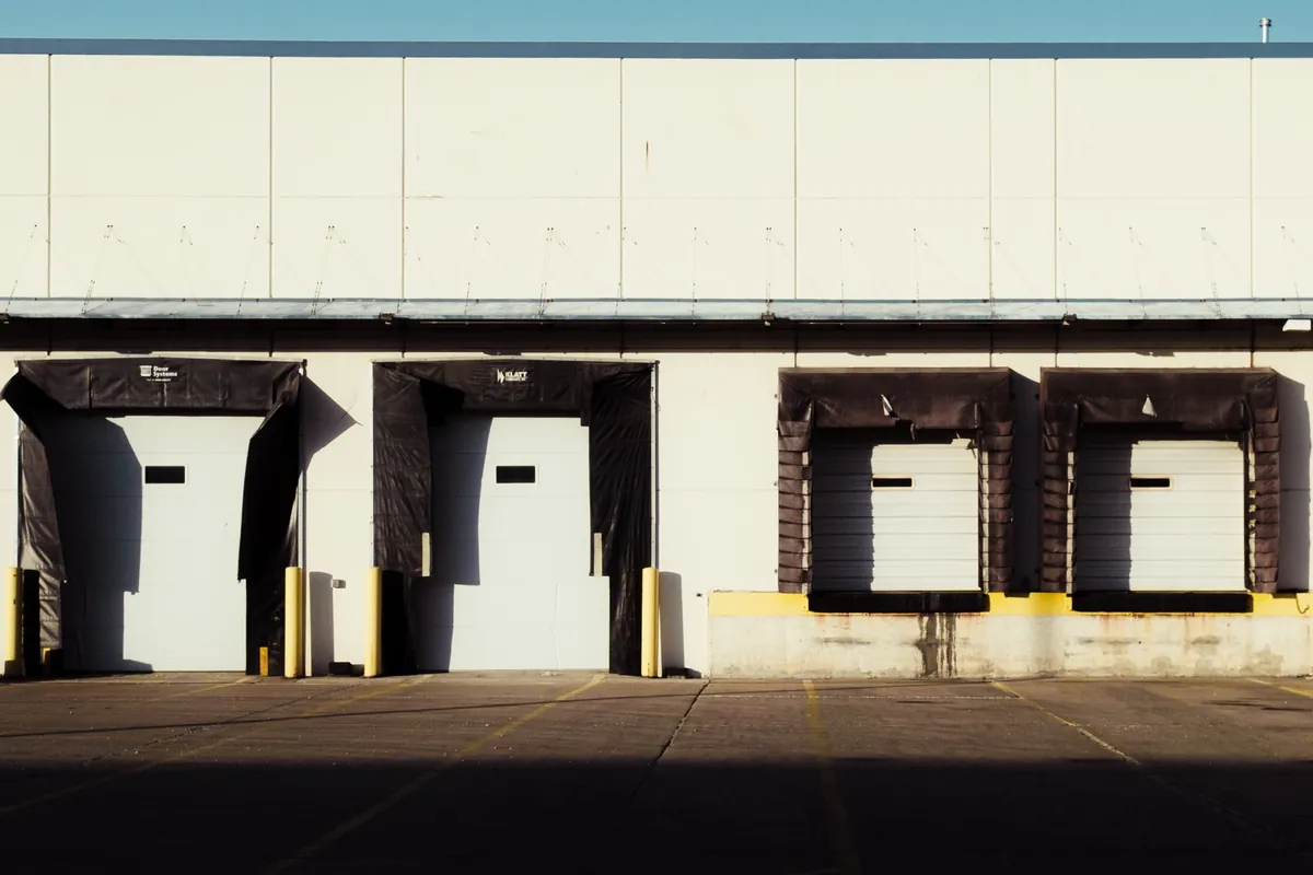 Warehouse building exterior with loading dock doors and ground-level sectional doors