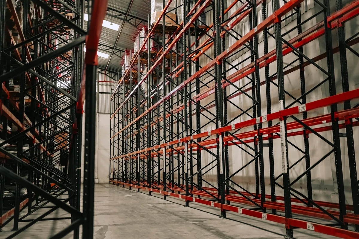 Warehouse interior with rows of pallet racking between storage and production zones