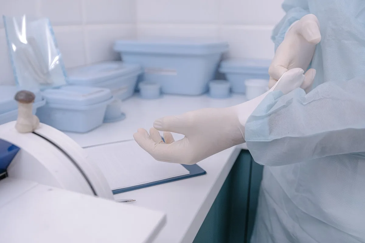 Operator pulling on cleanroom gloves inside a gowning area