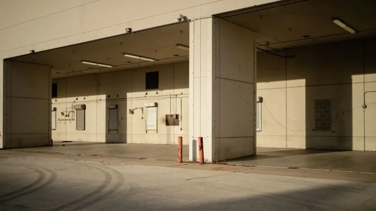 Empty industrial loading dock with sunlight casting shadows across the concrete apron