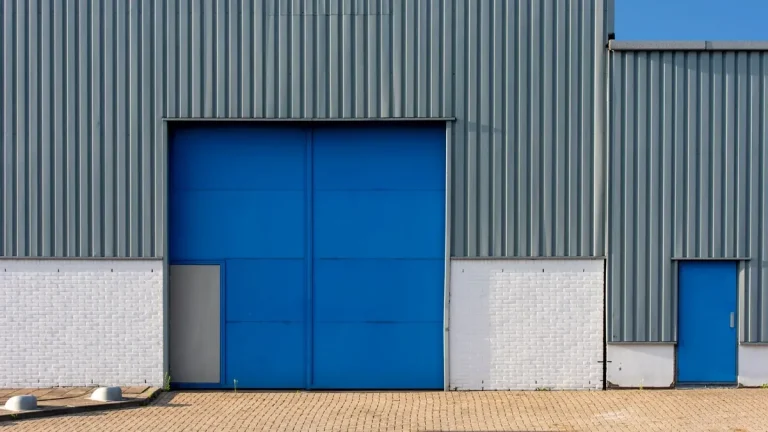 Blue and gray metal warehouse exterior with large industrial roller doors