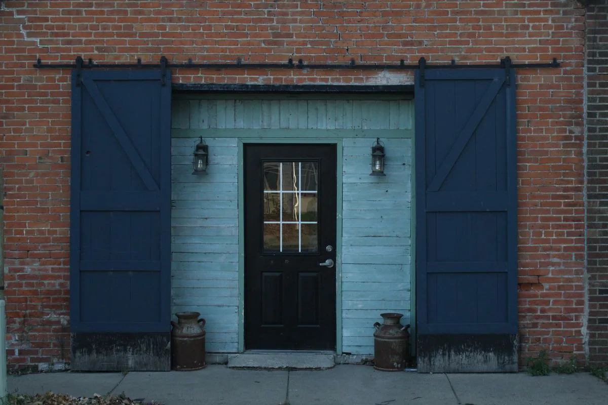 Blue wooden sliding doors running on an overhead steel track on a brick facade