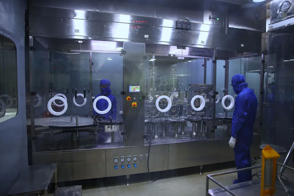 Workers in protective gear inside a sterile pharmaceutical manufacturing plant