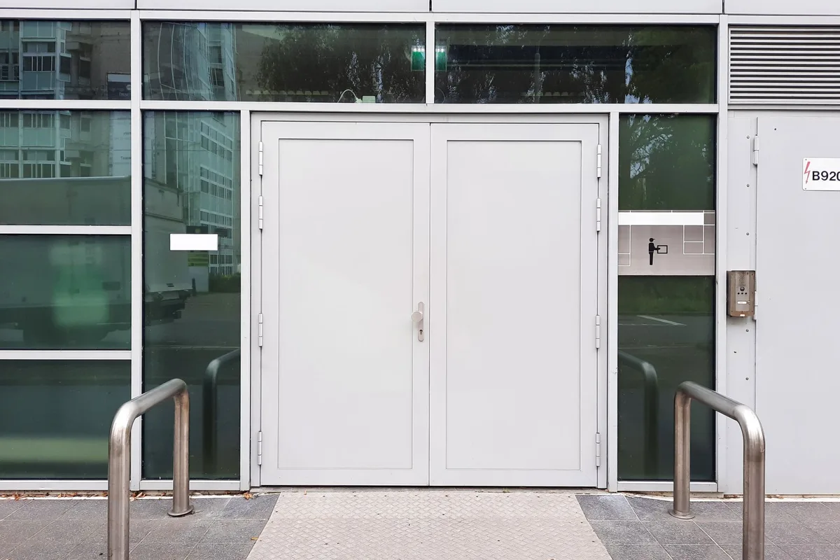 Flush white hygienic double door leaves on an industrial building, smooth cleanable surfaces with minimal exposed hardware