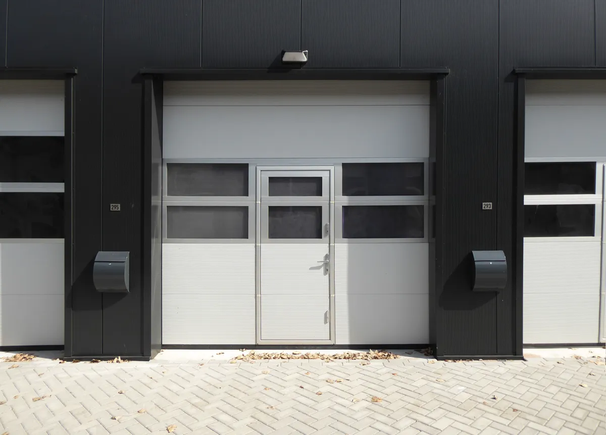Porte industrielle sectionnée isolée montée sur une ouverture de bâtiment commercial