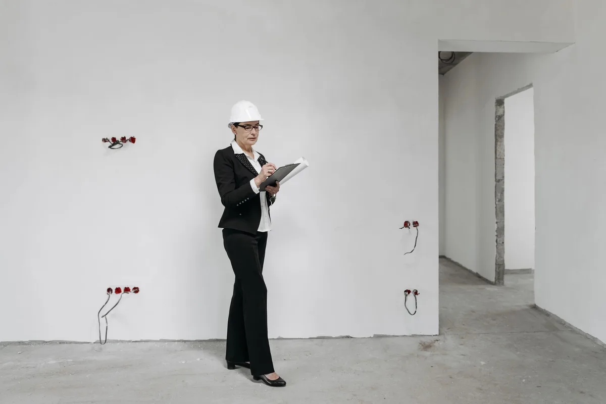 Inspector with a hard hat and clipboard documenting a doorway before handover