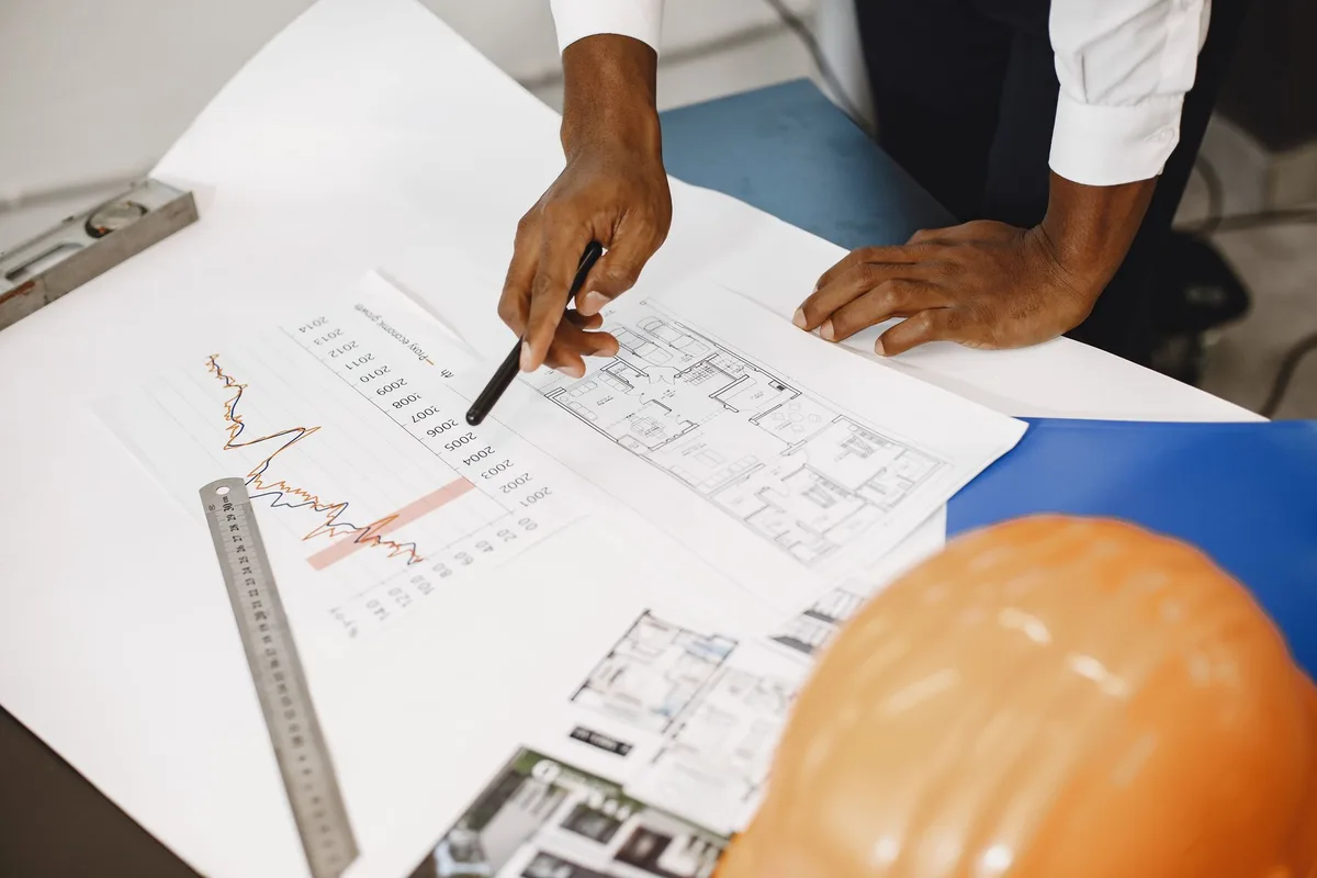 Engineer pointing at a floor plan and cost chart during a door budget review