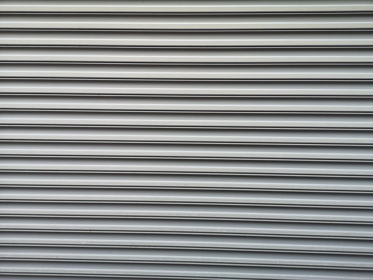Primer plano de láminas horizontales corrugadas de metal para persiana enrollable en gris claro